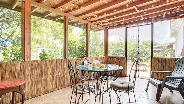 An outdoor patio with a round table and chairs, surrounded by wooden beams and string lights. - 💎Red Rooster cottage🌅💎🏄🏽‍♂️ (Port Orange)