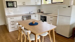 Une cuisine moderne avec des meubles blancs, un four à micro-ondes encastré, un évier, une cuisinière et un réfrigérateur.