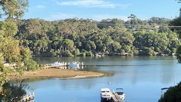 Un lac où sont amarrés des bateaux, entouré d’une forêt dense et sous un ciel dégagé.
