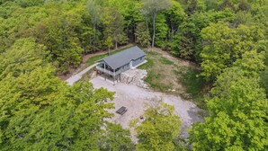 A house surrounded by dense forest, with a stone foundation and a covered porch. - Livin' the Dream in Fish Creek! (Fish Creek)