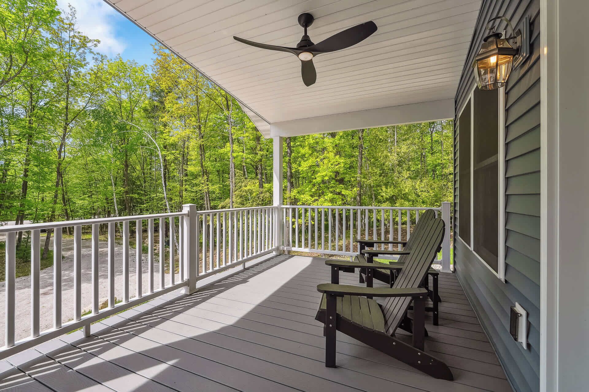 A covered porch with a ceiling fan, a table, and two chairs.