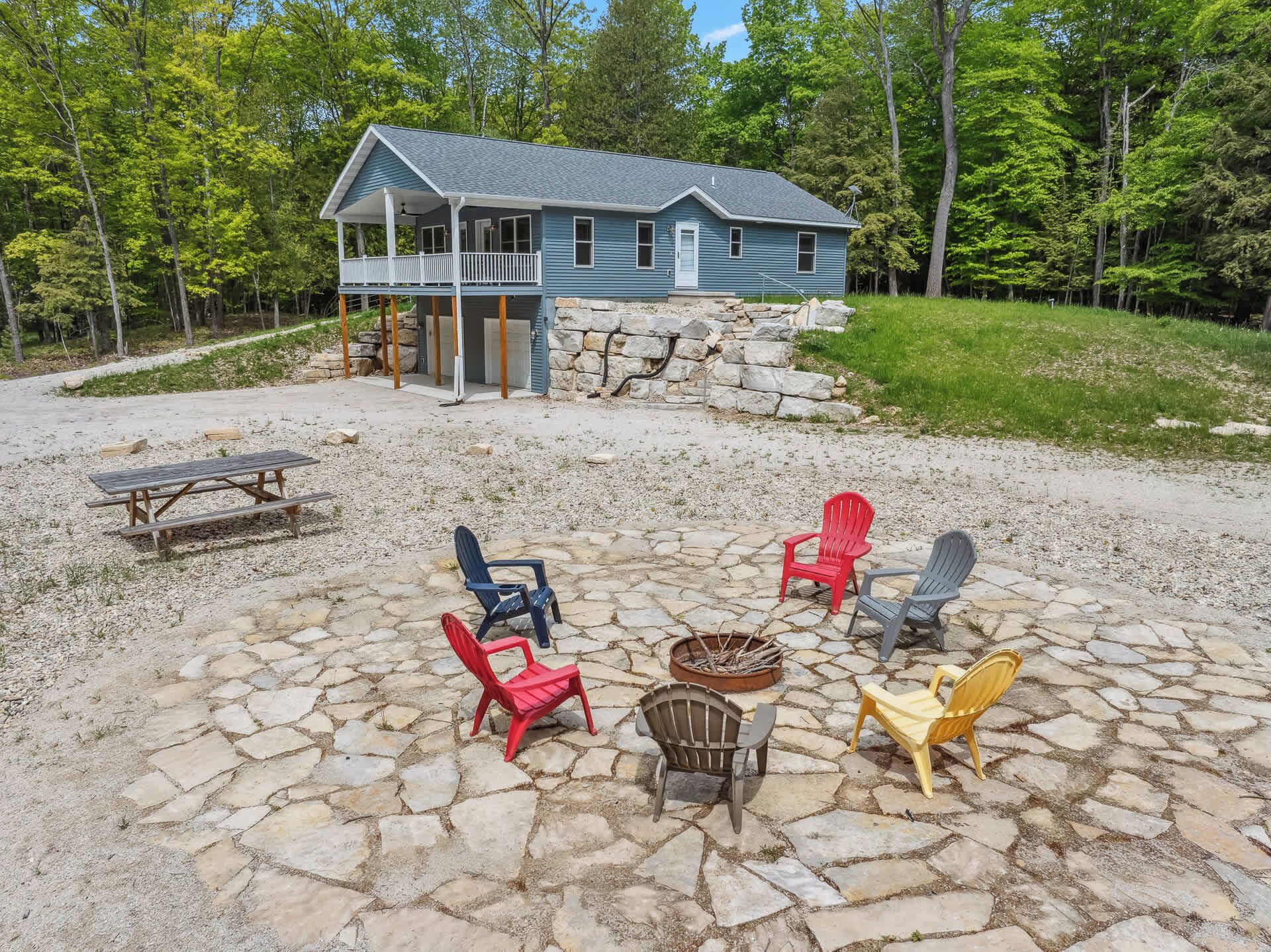 A house with a porch, stone patio, and outdoor seating.