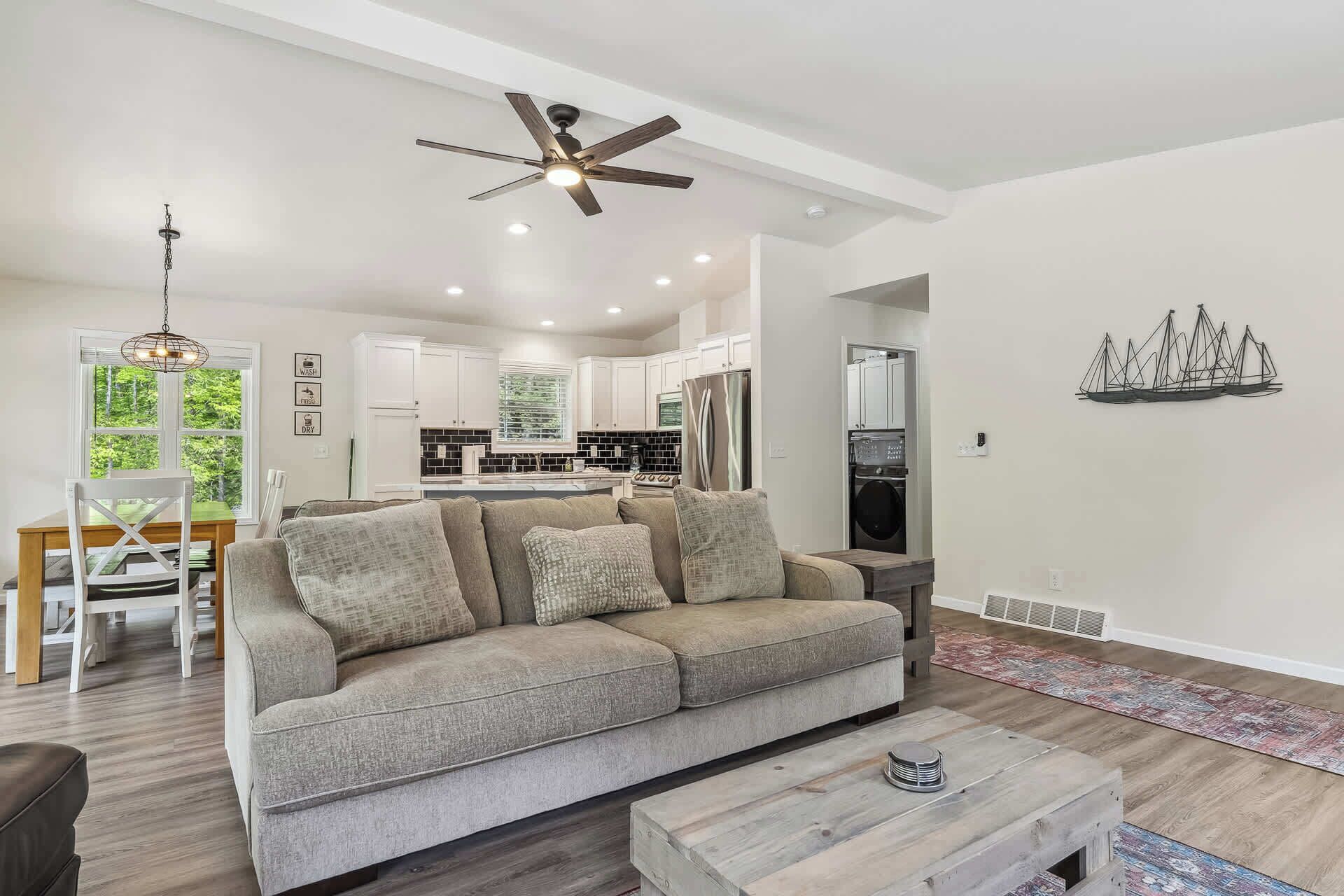 A living room with a sofa, coffee table, and a dining area with chairs and a table.