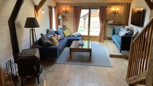 A cozy living room with a large sofa, a smaller sofa, a coffee table, and a wood-burning stove. - Savoyard Farmhouse - Sleeps 14, Garden & Parking (Araches-la-Frasse)