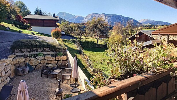 A patio area with outdoor furniture, a stone wall, and a view of mountains in the background. - Savoyard Farmhouse - Sleeps 14, Garden & Parking (Araches-la-Frasse)
