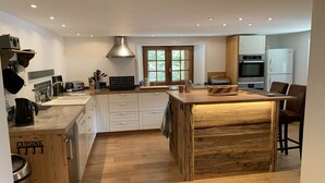 A modern kitchen with white cabinetry, a wooden island, and built-in appliances. - Savoyard Farmhouse - Sleeps 14, Garden & Parking (Araches-la-Frasse)