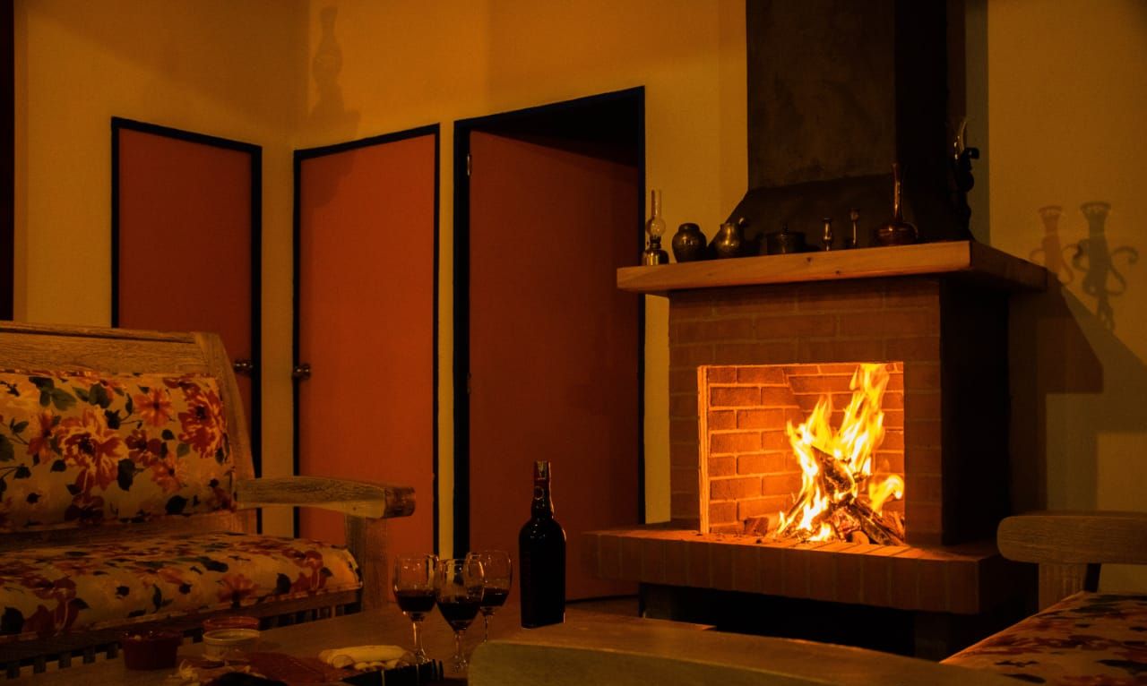 Um quarto acolhedor com lareira, um sofá e uma mesa com copos e uma garrafa.
