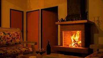 Um quarto acolhedor com lareira, um sofá e uma mesa com copos e uma garrafa.