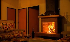 A cozy room with a fireplace, a sofa, and a table with glasses and a bottle. - Country house in Santa Elena, very close to Medellin (medellin)