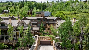 A multi-story house with a stone facade, a garage, and a driveway leading to a stone staircase. - Year-Round Fun - Central Location, Private Hot Tub & 5-Min Walk to Free Shuttle! (Park City)