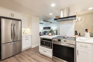 Una cocina moderna con electrodomésticos de acero inoxidable, armarios blancos y una isla central.