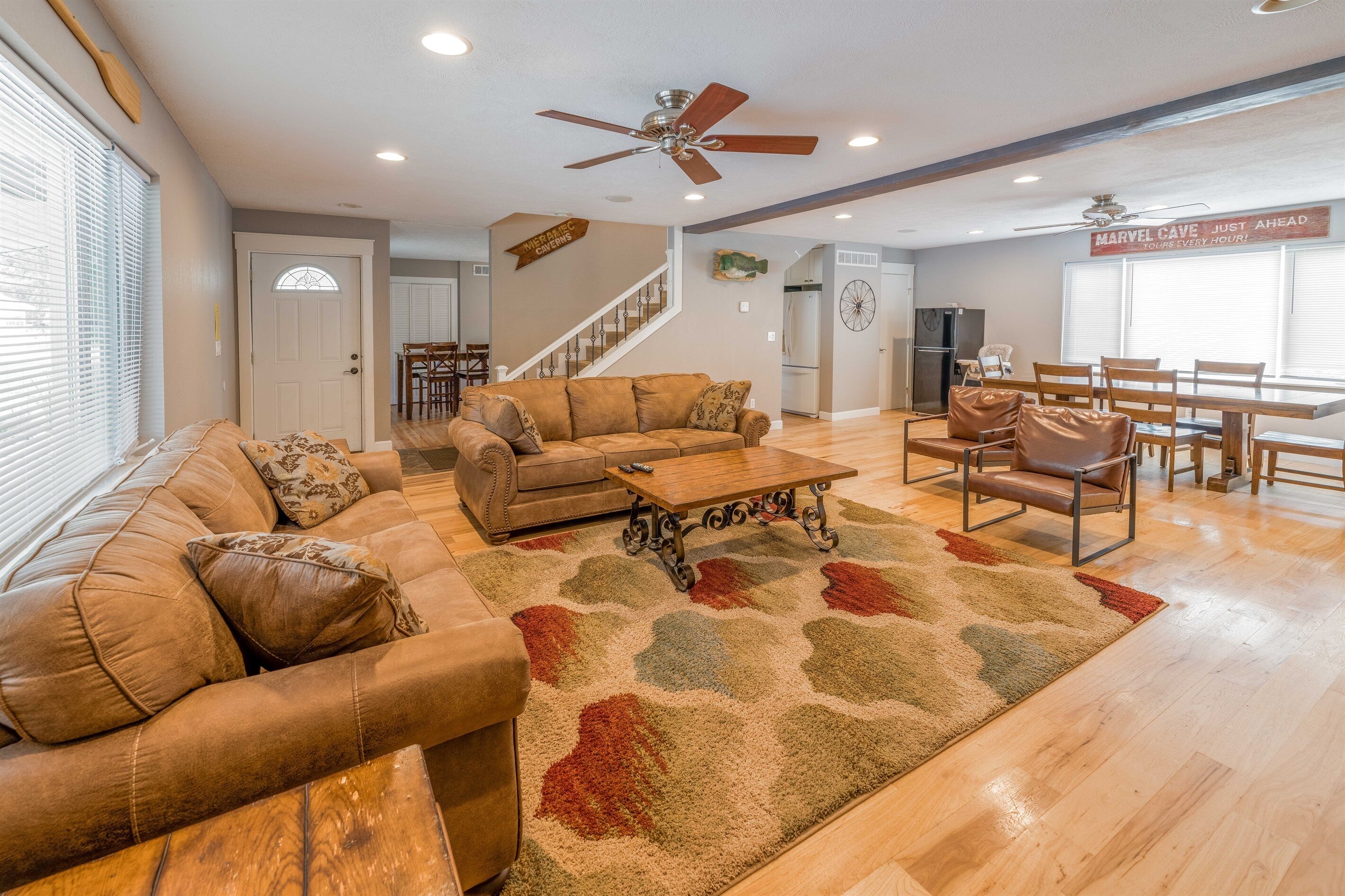 A spacious living room with a large sofa, a coffee table, and a dining area with chairs and a table.