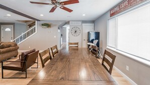 Ein geräumiger Essbereich mit einem langen Holztisch und Stühlen, einem Deckenventilator und einem Schild mit der Aufschrift 'Marvel Cave Every Hour'.