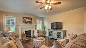 Un salon avec une cheminée, un ventilateur de plafond, un téléviseur et un ensemble de canapés.