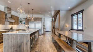 Una cocina moderna con una isla grande, suelo de madera e iluminación colgante.