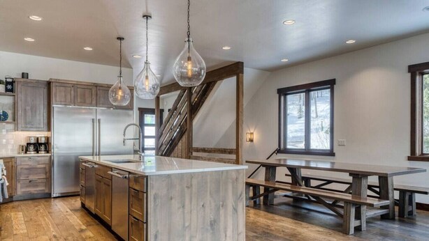 Una cocina moderna con una isla grande, armarios de madera e iluminación colgante.