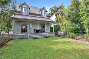 A two-story house with a covered porch, a dining area, and a well-maintained lawn. - Russell Cottages - Russell Holiday Home (Russell)