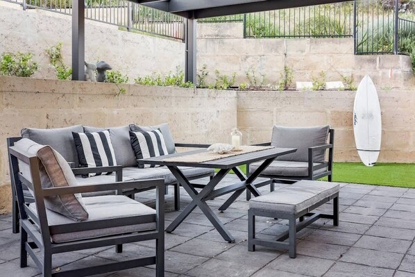 An outdoor patio with a sofa set, a table, and chairs.