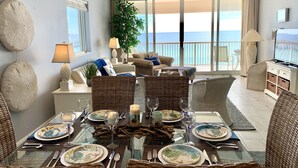 Comedor con una mesa de vidrio dispuesta para seis personas, rodeado de sillas de mimbre.
