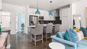 Une cuisine moderne dotée d’un îlot central, de tabourets de bar et de luminaires suspendus.