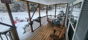 A wooden deck with a table and chairs, surrounded by snow-covered trees. - Chandler Hill Base Camp - Enjoy A Nature Getaway In This Rustic Home In The Mountains, 10 Minutes From Sunday River Ski Mountain! 4 Bedroom Home by RedAwning (Bethel)