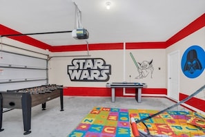 Ett rum med ett fotbollsspel, ett bordtennisbord och inredning med Star Wars-tema.