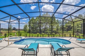 A covered outdoor swimming pool with lounge chairs and a view of trees and hills. - 6 Bed 4 Bath Solterra Beautiful Home! 6 Bedroom Villa by RedAwning (Davenport)