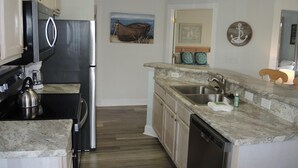 A modern kitchen with a stainless steel refrigerator, a kettle, and a dishwasher. - 406m 1 Bedroom Condo by RedAwning (Calabash)