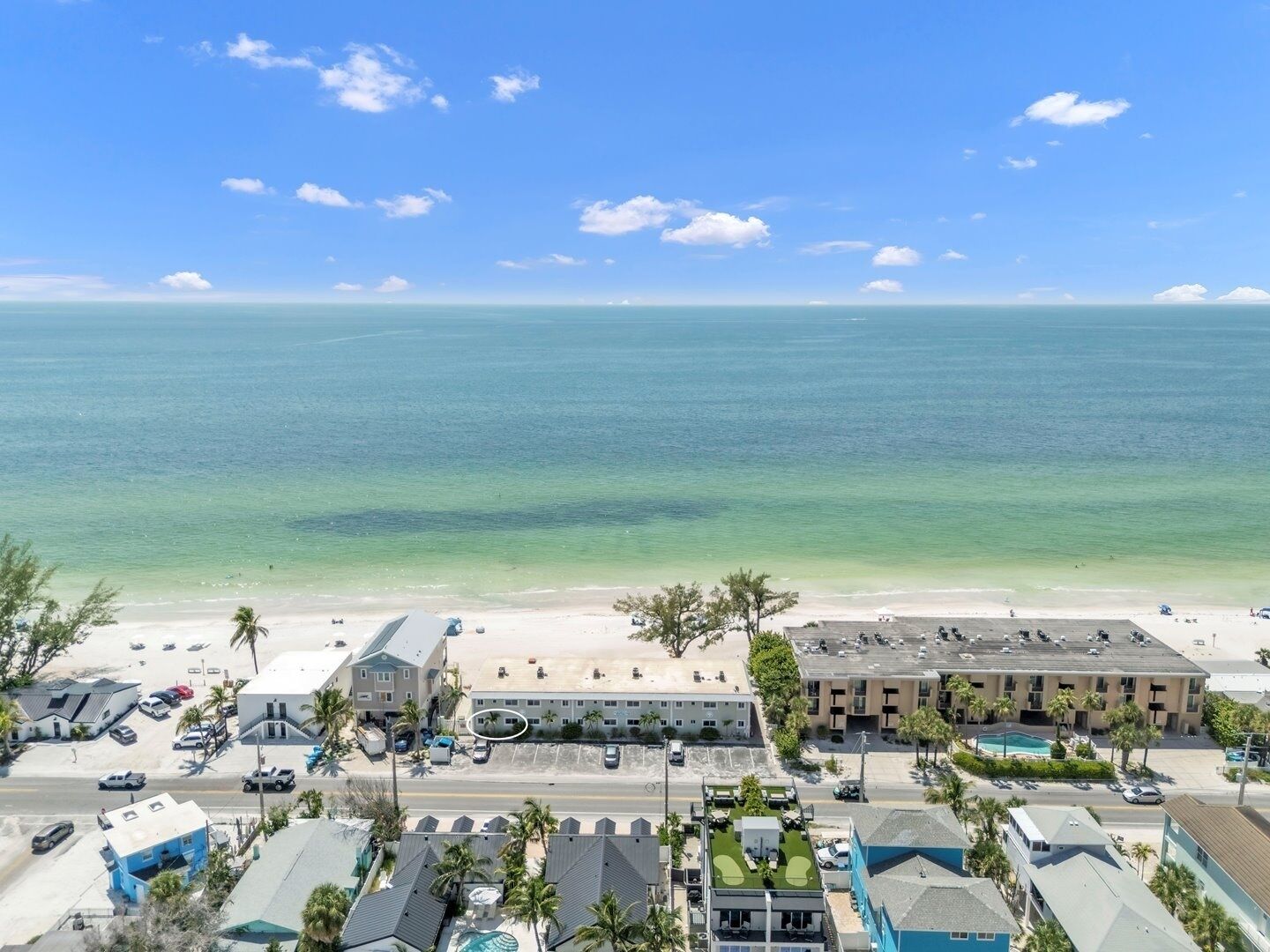 Een kusthotel met uitzicht op het strand, diverse parkeerplaatsen en een zwembad.