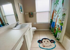 A bathroom with a white sink, toilet, and a monkey-themed rug. - Golf Views By The Pool! Southern Dunes Golf Home 5 Bedroom Villa by RedAwning (Haines City)