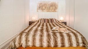 A bedroom with a fur-covered bed, two bedside lamps, and a painting on the wall. - Les Genepis (Val Claret) by Interhome (Tignes)