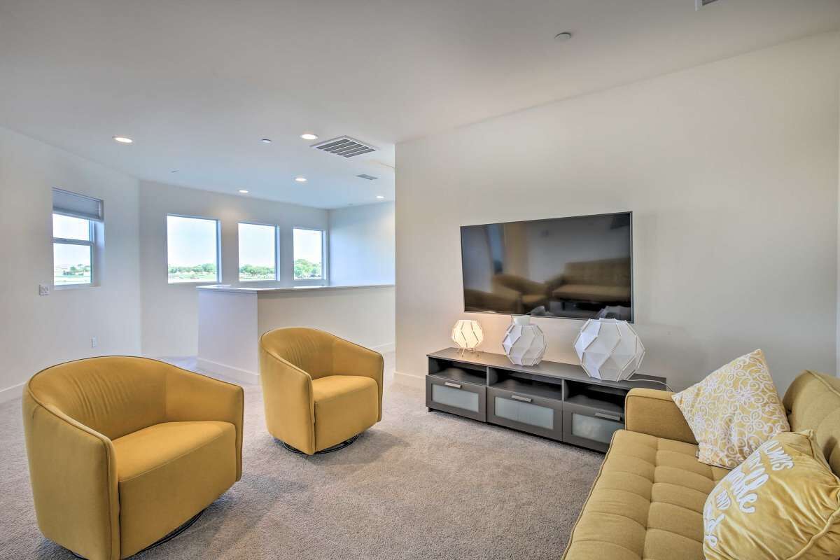 A modern living room with a sofa, two armchairs, a TV, and a console table with decorative items.