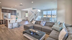 A spacious living area with a modern kitchen, a large sofa set, and a staircase leading to an upper level.