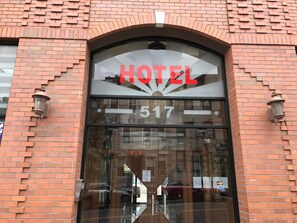 A hotel entrance with a large glass door, the word "HOTEL" above the door, and the number 517 below. - Phoenix Hotel (Brooklyn)