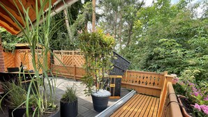 Una terraza de madera con plantas en macetas y un cerco de madera.