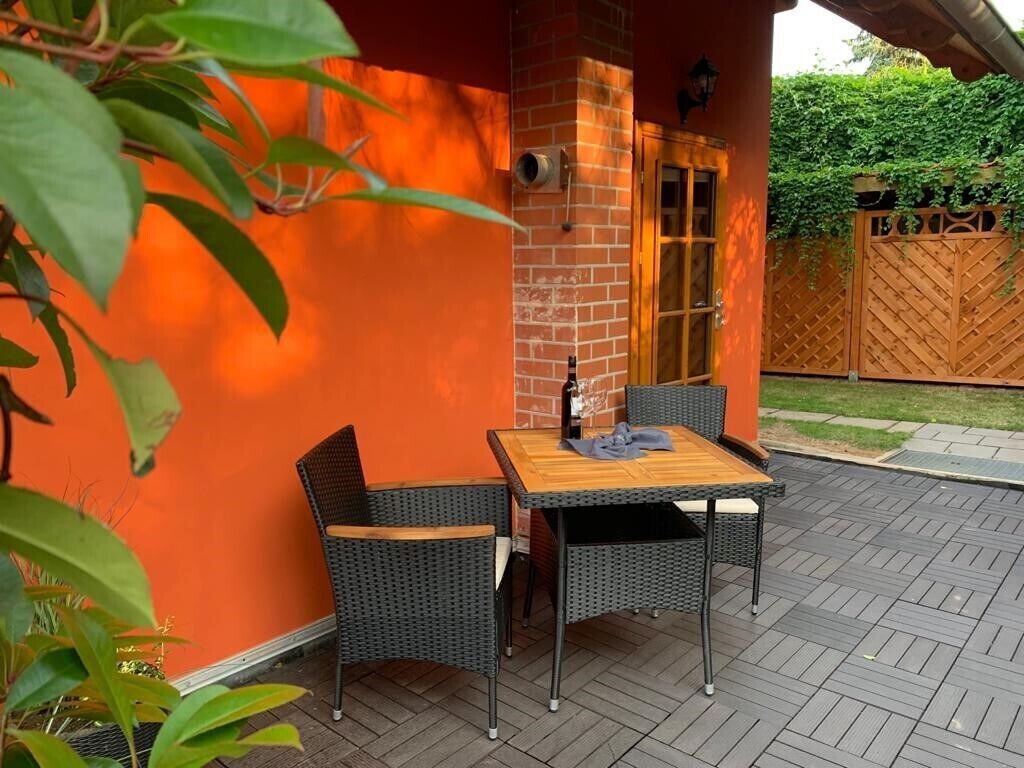 Eine Terrasse im Freien mit einer Ziegelwand, einer Holztür und einem Tisch mit Stühlen.