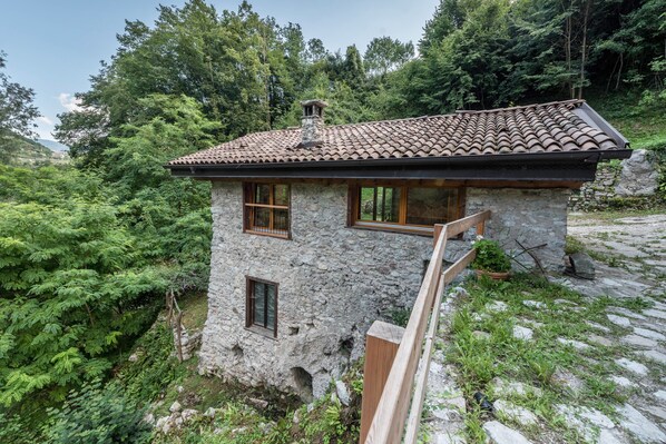 A stone house with a tiled roof, wooden windows, and a stone chimney.