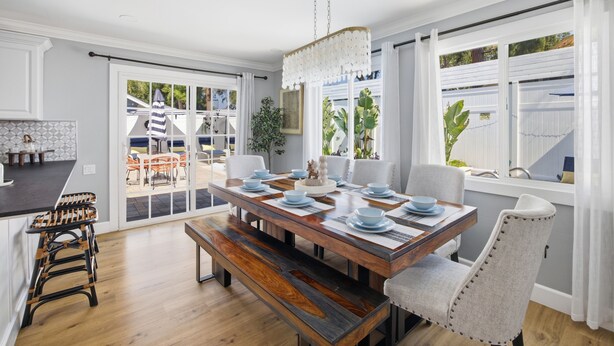 A dining area with a wooden table, white chairs, and a chandelier. - Laguna vacation home pool Sauna jacuzzi (Laguna Hills)