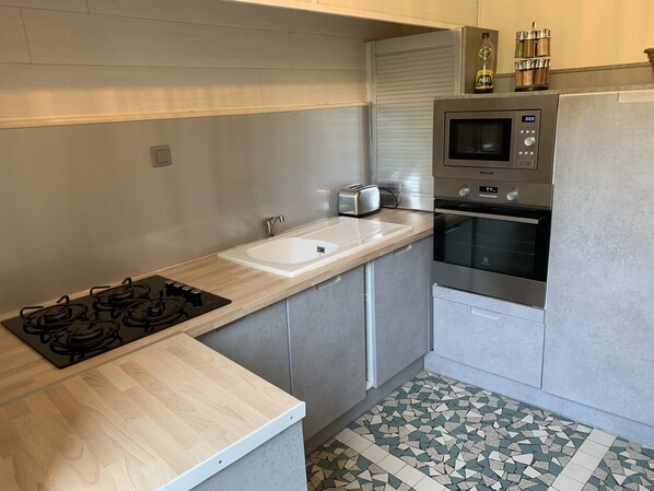 A modern kitchen with a gas stove, a sink, a built-in oven, and a microwave. - Riverside villa in historical village (Ségur-le-Château)