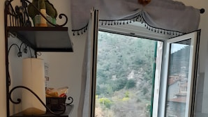 Une salle de bain avec une fenêtre, un porte-serviettes, une étagère avec des articles de toilette et un radiateur.