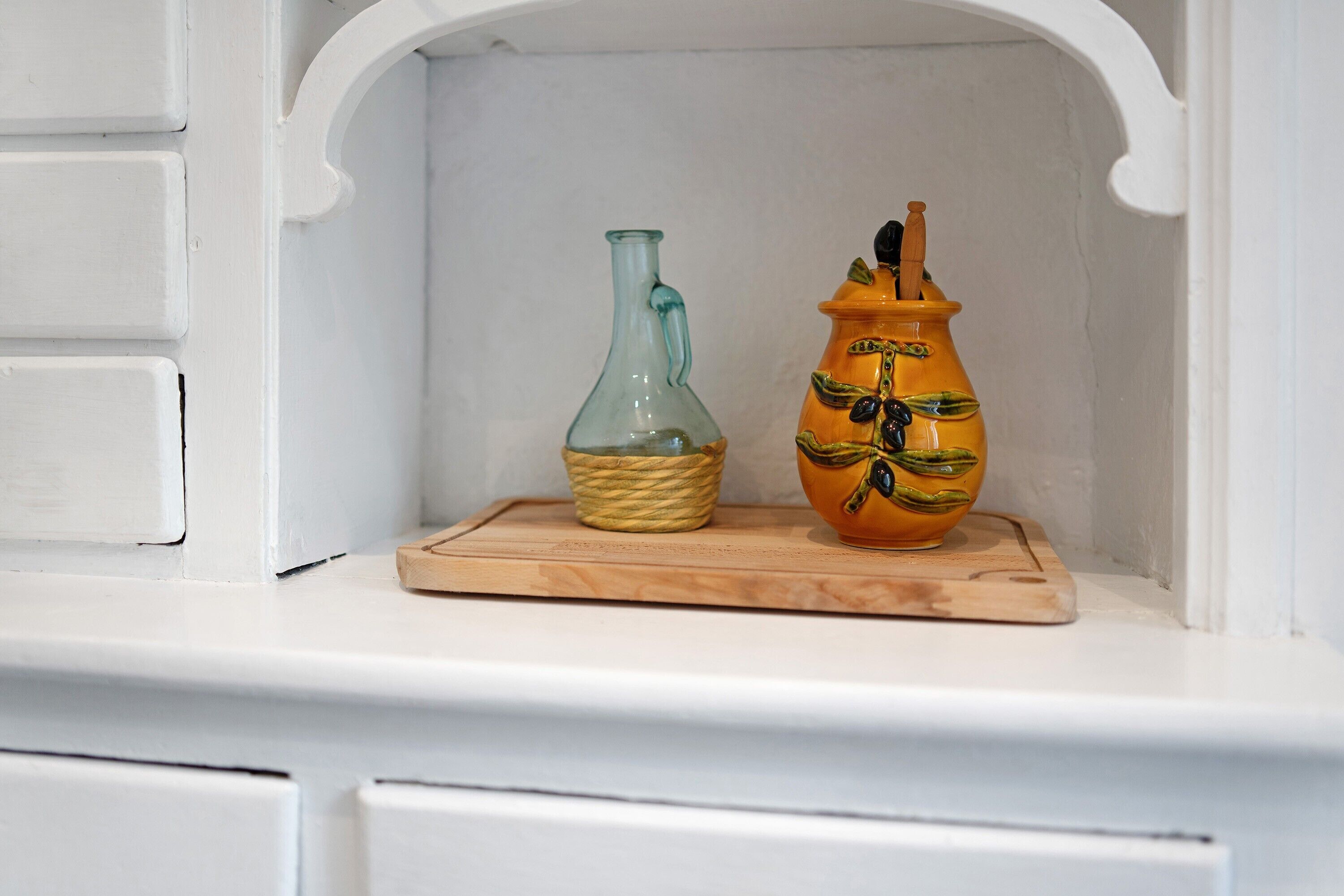 Deux vases en céramique, posés sur un plateau en bois, dans une étagère blanche.