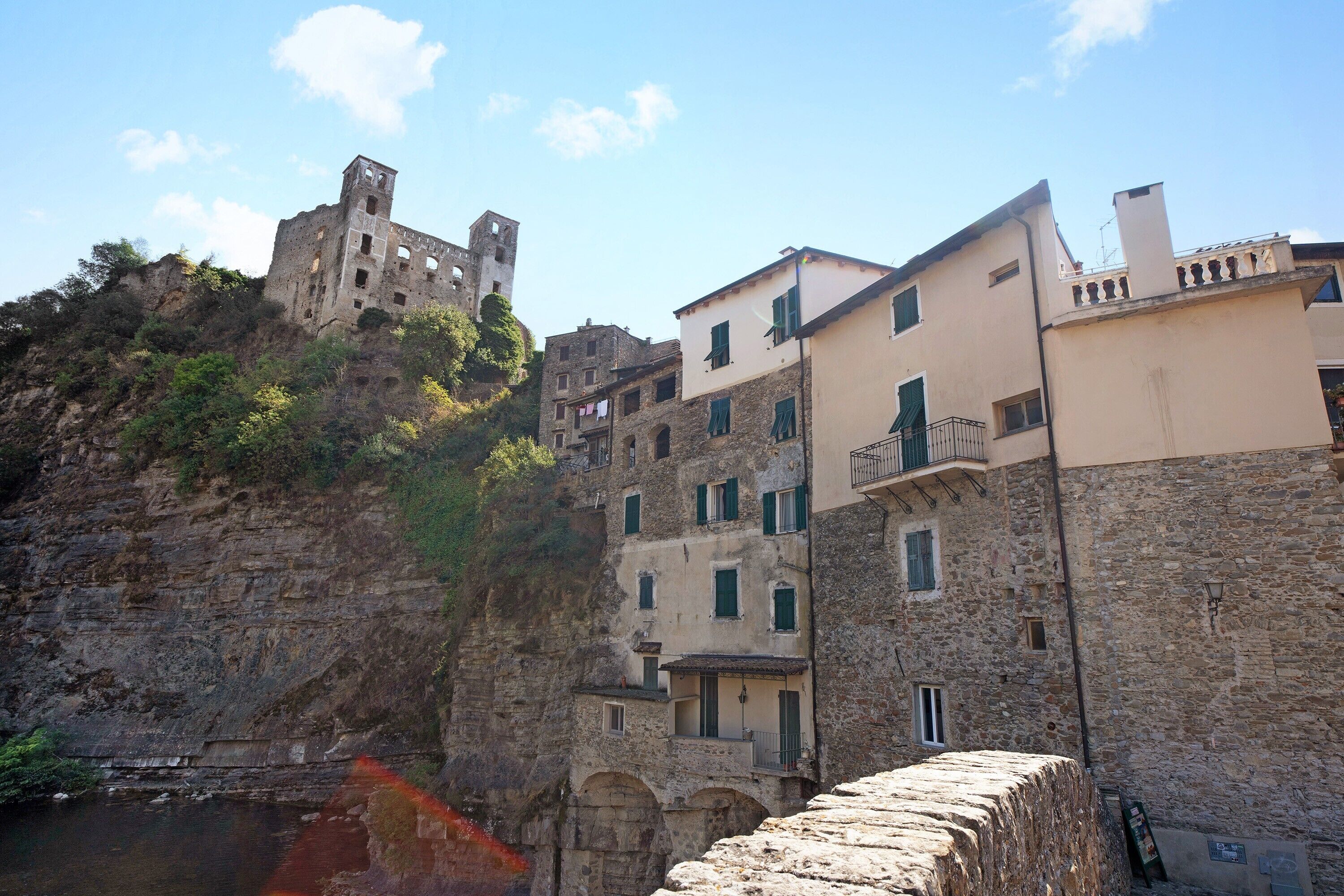 A coastal town with historic stone buildings, a prominent castle on a cliff, and a stone bridge.