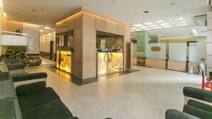 Um lobby amplo com balcão de recepção, área de estar e extintor de incêndio.