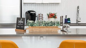A modern kitchen with a central island, a coffee machine, a flower vase, and a sign reading "relax and enjoy the wifi".