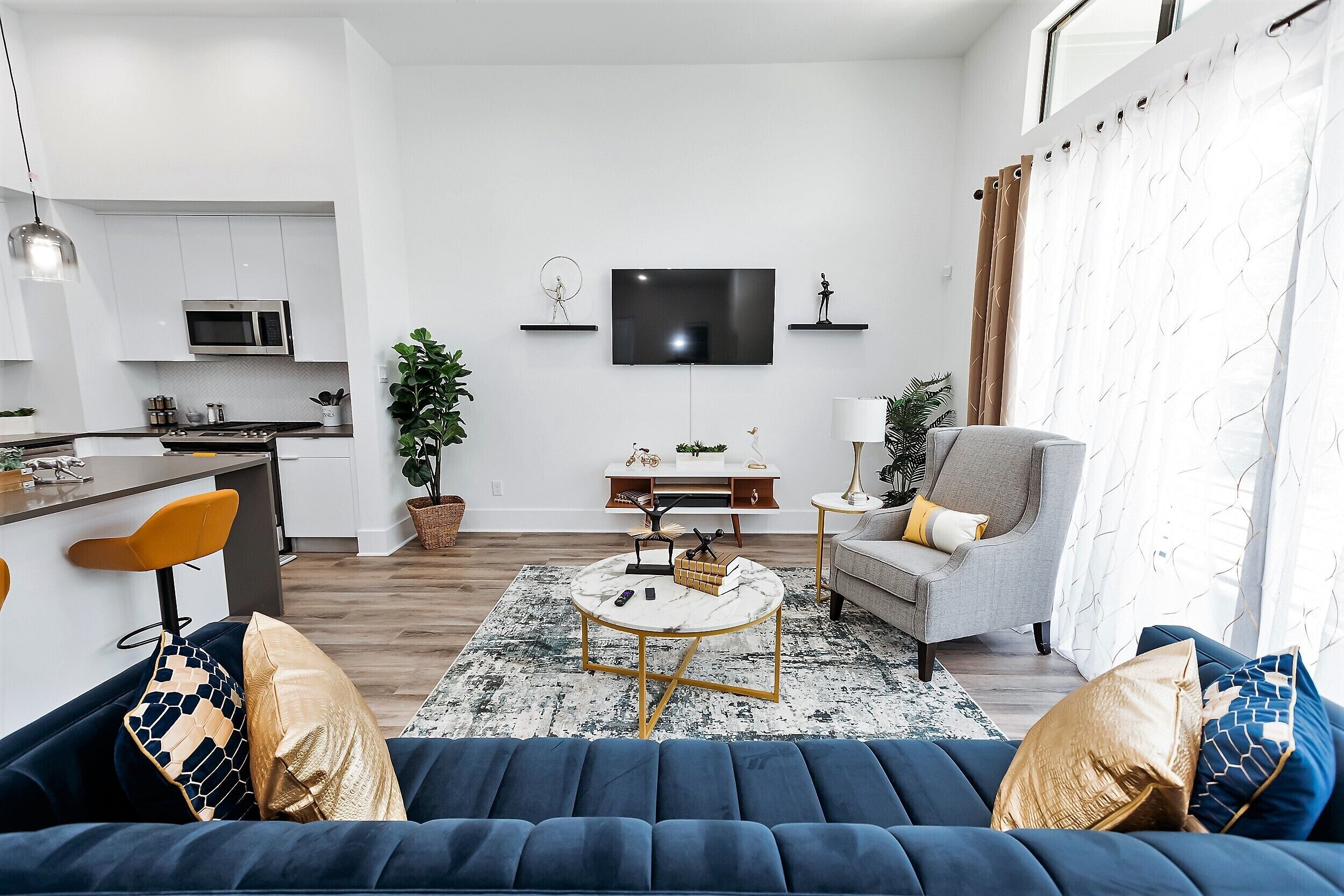 Una sala de estar moderna con un sofá azul, una mesa de centro y un televisor montado en la pared.