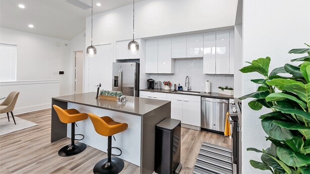 A modern kitchen with white cabinets, stainless steel appliances, and a central island with bar stools.