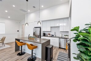 A modern kitchen with white cabinets, stainless steel appliances, and a central island with bar stools.