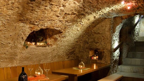 A rustic interior with stone walls, wooden benches, and tables. - WeinMotel Simon 1 a (Alzenau)