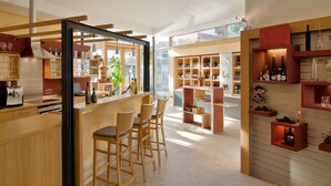 A modern kitchen with wooden bar stools, a dining area, and a wine display. - WeinMotel Simon 1 a (Alzenau)