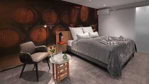 A modern bedroom with a large bed, a nightstand, a chair, and a wall mural of wine barrels. - WeinMotel Simon 1 a (Alzenau)